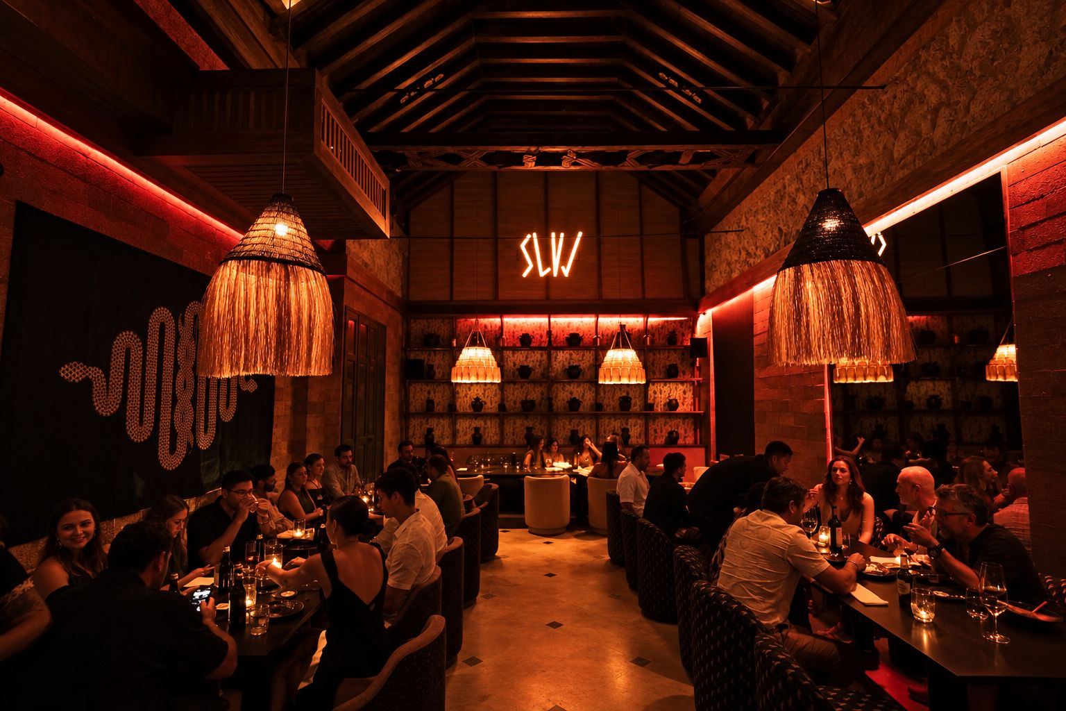 The SLVJ dining room at Casa Salvaje at night: woven pendant lamps, red neon light and a full room.