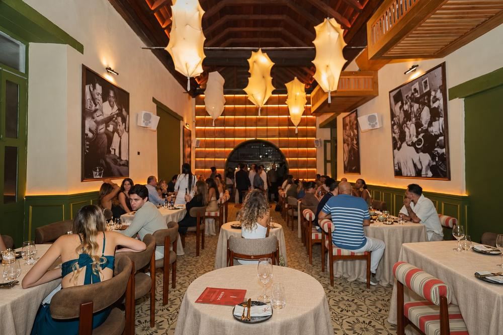 The Kanibal dining room at night, full of guests, with white walls, green panelling and paper lanterns.